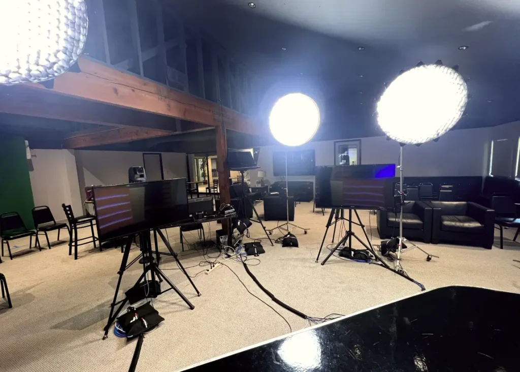 Video production studio with bright lighting, monitors, cables, and seating arranged for filming or live streaming