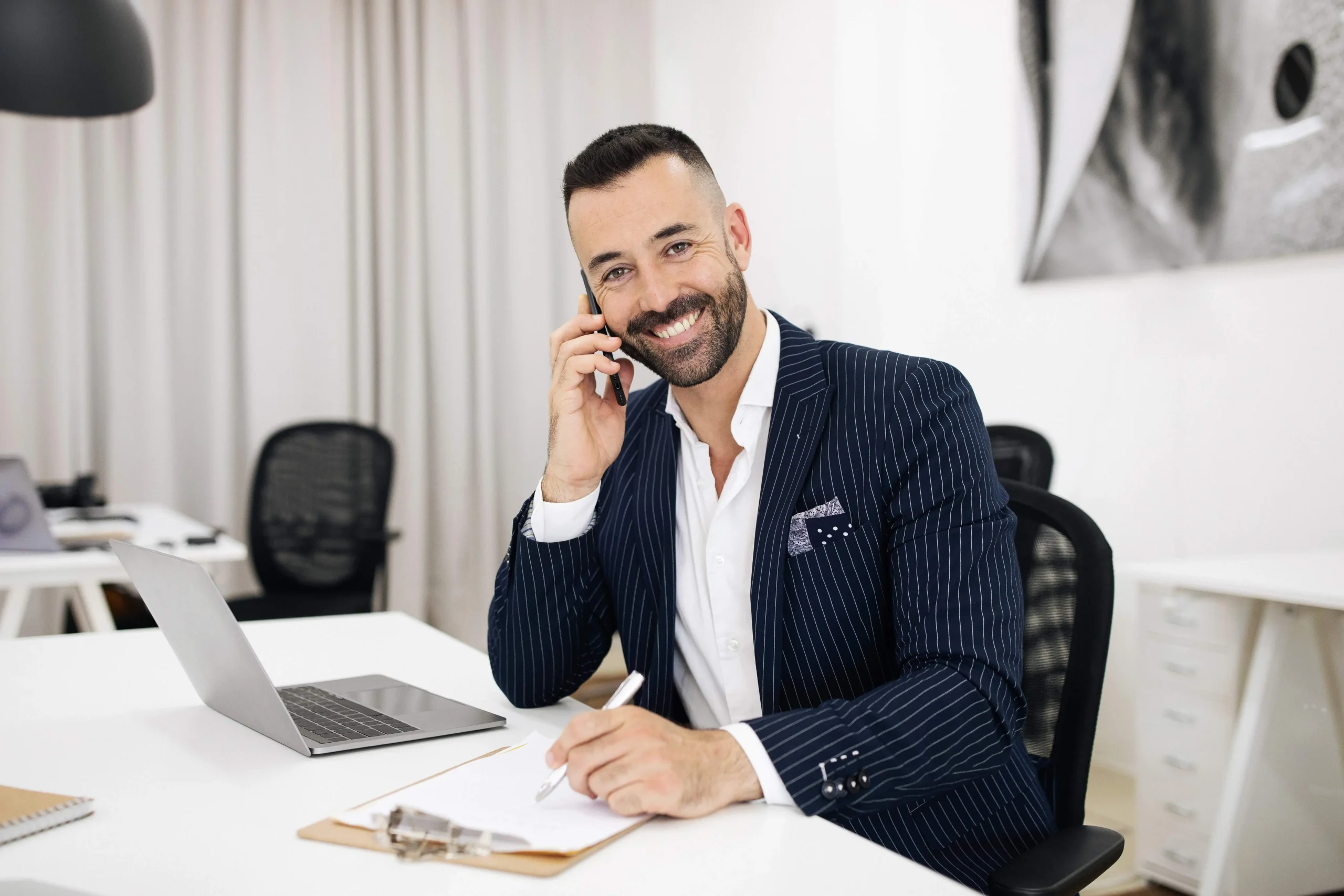 smiling luxury real estate agent in suit with beard working